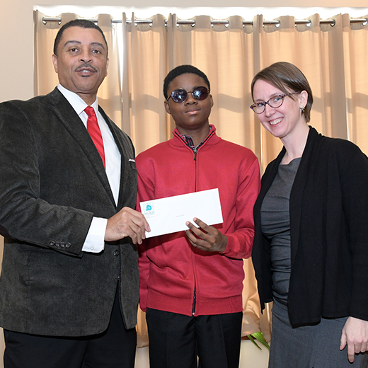 Kenneth and lady handing check to young man