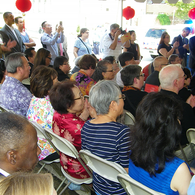 Community members sitting in chairs under a tent