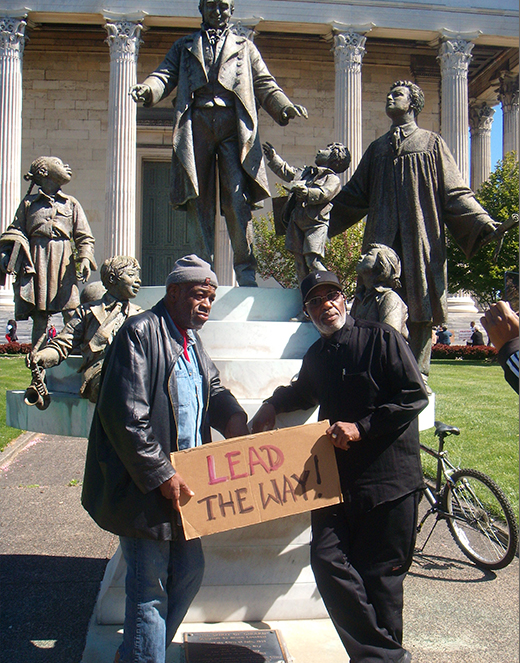 2 men holding sign that says Lead the Way